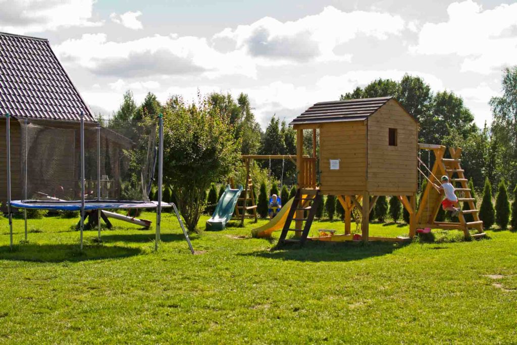 Plac zabaw dla dzieci z domkiem, piaskownicą, trampolinami oraz huśtawkami